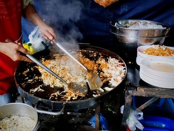 Midsection of person preparing food on barbecue grill