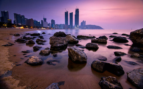 Panoramic view of sea and buildings against sky during sunset
