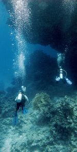 Scuba divers swimming in sea over corals