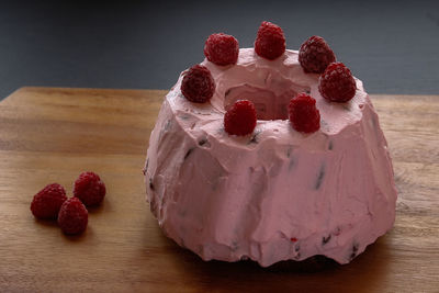 Close-up of pink cake garnish with raspberries on table