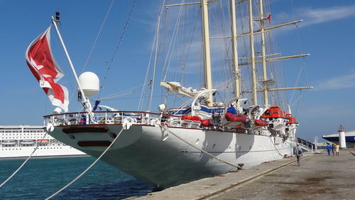 Sailboats moored in sea against sky