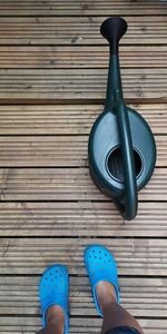 Low section of woman standing by watering can on wooden boardwalk