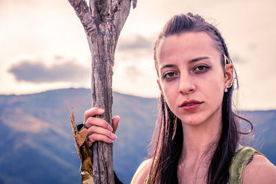 Portrait of young woman standing against sky