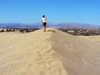 Rear view full length of tourist walking on sand dune at grand canary