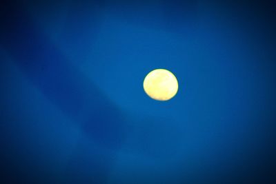 Low angle view of half moon against blue sky