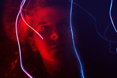 Reflection of young man on illuminated glass