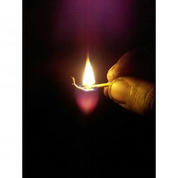 Close-up of lit candle in dark room