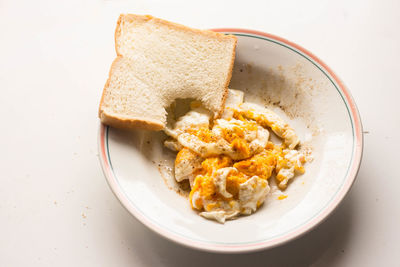 Breakfast scrambled eggs and bite bread in white dish in morning