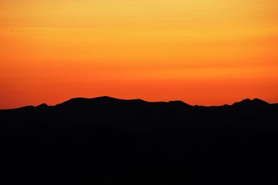 Silhouette mountains against orange sky