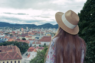 Rear view of woman looking at cityscape against sky