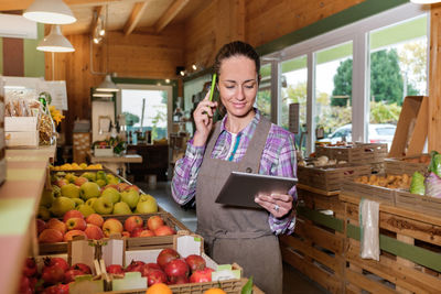 Fruit seller talking on phone while standing at shop