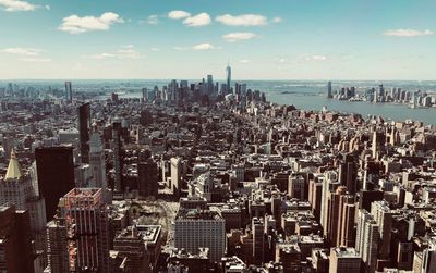Aerial view of city by sea against sky
