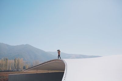 Man standing on rooftop against sky