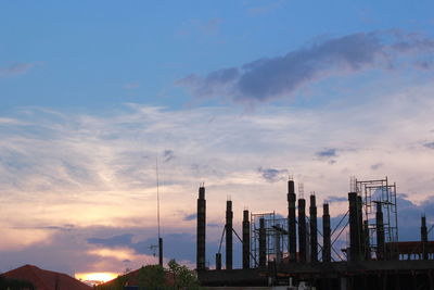 Cranes at construction site against sky during sunset