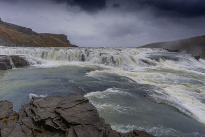 Scenic view of waterfall against sky