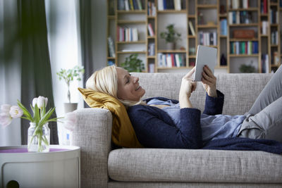 Woman using digital tablet, relaxing on couch