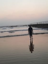 Silhouette man standing on beach against sky during sunset