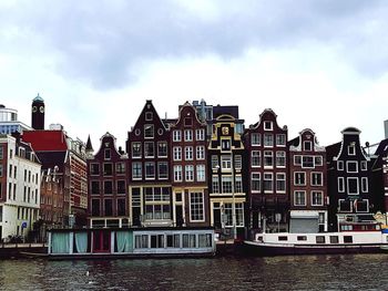 Buildings by river against sky