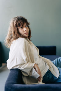 Portrait of young woman sitting on bed at home