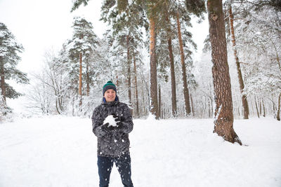 A young man with a snowball in his hand is having fun, swinging for a throw. winter family 