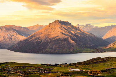 Scenic view of lake and mountains against sky during sunset