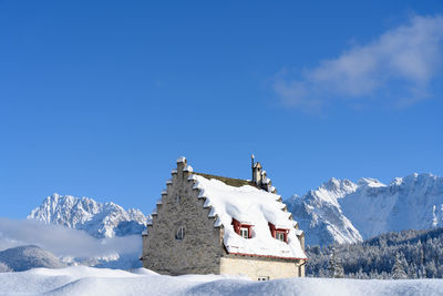 Snow covered buildings against blue sky