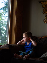 Boy looking at camera while sitting on sofa at home