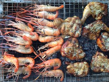 Directly above shot of tiger prawns with chicken meat on barbecue grill