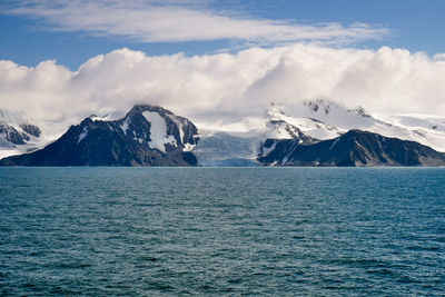 Scenic view of snowcapped mountains by sea against sky