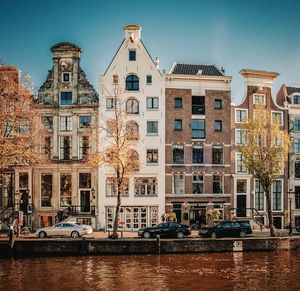 Buildings by canal against sky in city