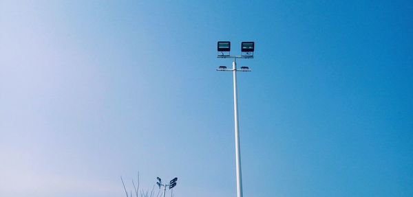 Low angle view of telephone pole against clear blue sky