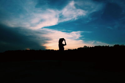 Silhouette man standing on field against sky during sunset