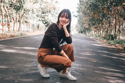 Portrait of beautiful young woman sitting on road