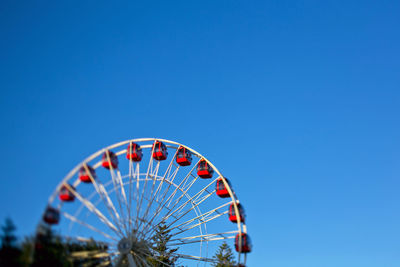 Low angle view of ferris wheel against blue sky