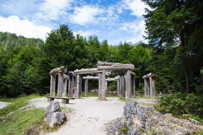 Built structure in forest against cloudy sky