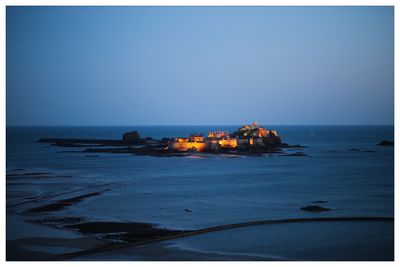 Built structures in calm sea against clear sky