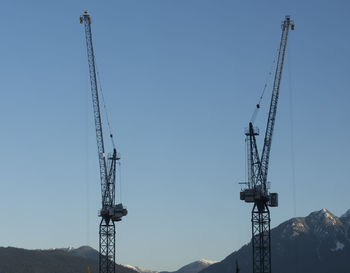 Low angle view of crane against clear blue sky