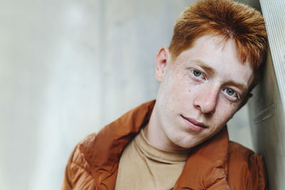 Redhead boy leaning on wall