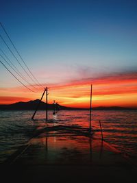 Silhouette sailboat in sea against sky during sunset