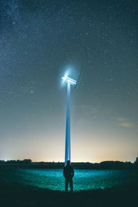 Person standing on field against sky at night