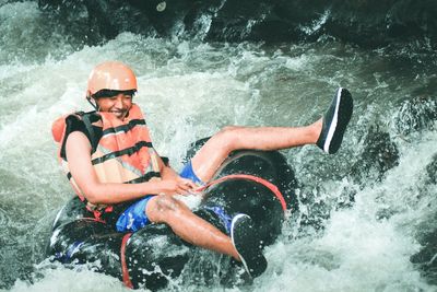 Smiling man sitting on inflatable ring in river