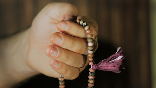 Cropped hand of person holding bead necklace