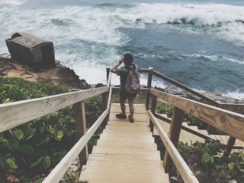 Woman standing on staircase towards sea