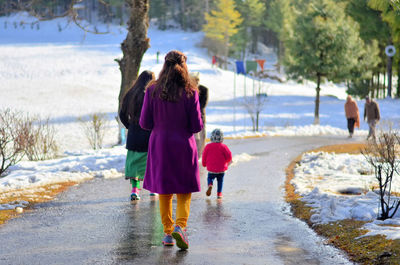 Rear view of girls walking on snow covered landscape