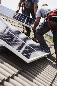 Electrician coworkers installing solar panels on rooftop