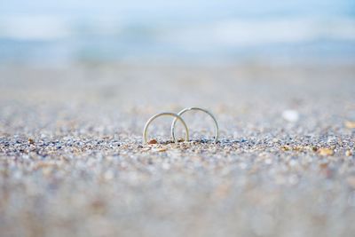 Surface level shot of wedding rings in sand at beach during sunny day