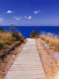 Boardwalk leading towards sea against sky