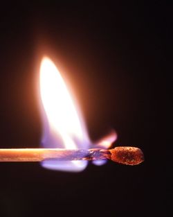 Close-up of lit candle against black background