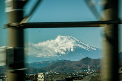 Panoramic view of buildings and mountains against sky seen through window