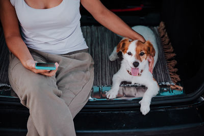 Man holding dog while sitting on car